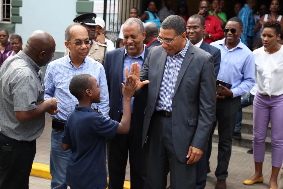 Prime Minister Andrew Holness high-fives a youngster while touring sections of Falmouth with Government Officials and Stakeholders.